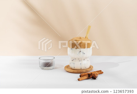 Korean whipped drink Dalgona coffee in a glass on a white beige background with spices and shadow. Korean whipped drink Dalgona coffee in a glass on a white beige background with spices and shadow. 123657393