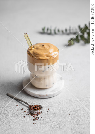 Korean whipped drink Dalgona coffee on a light background with spoon and morning shadow. 123657398