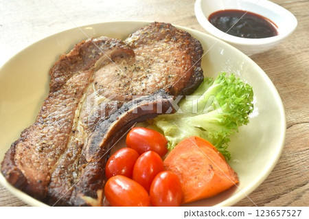 grilled black pepper pork chop steak and lettuce with tomato couple boiled carrot on plate dipping barbecue sauce in cup 123657527