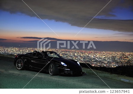 A shiny black convertible and a night view A shiny black convertible and a night view 123657941