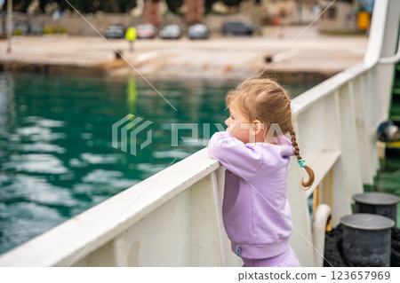 Little girl traveling with family by ferry. Crossing from one bank to another of Kotor bay in Montenegro 123657969