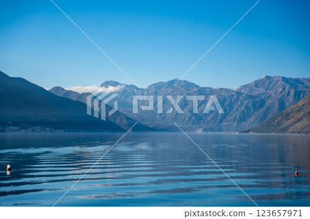 Bay of Kotor in Montenegro and the top of high snow-capped mountains, small settlements on the coast and the bright blue waters of the Adriatic Sea. 123657971