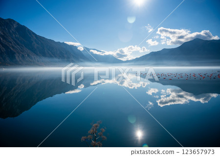 Mountains with clouds and their reflection in the still waters of the sea, separated by a strip of fog in winter morning Bay of Kotor in Montenegro 123657973