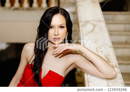 Elegant woman in red suit is standing on the big stairs. 123658266