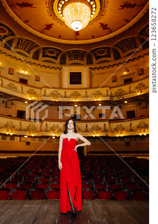 A luxurious actress in a red dress sings on stage with a microphone in her hands 123658272