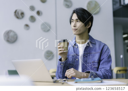 A young man working on a PC while drinking coffee from a paper cup in a cafe. Photo courtesy of Sky Perfect Tokyo Media Center A young man working on a PC while drinking coffee from a paper cup in a cafe. Photo courtesy of Sky Perfect Tokyo Media Center 123658517