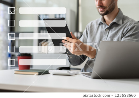 Business performance checklist concept, businessman using tablet and laptop doing online checklist survey, filling out digital form checklist. 123658660