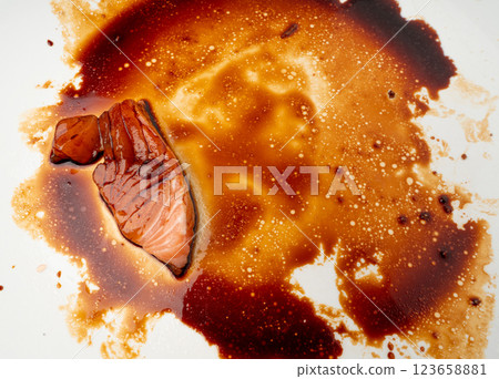 Spilled Soy Sause Leftovers with a Piece of Fish Isolated, Teriyaki Drops on White Plate, Oyster Sauce 123658881