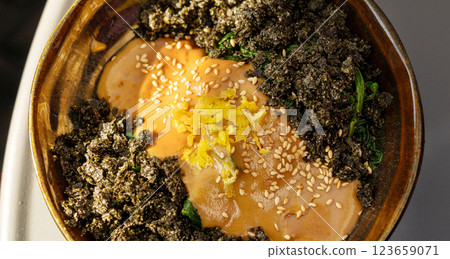 Vegetarian spinach salad closeup. Fried spinach with nori and tahini, vegan dish in sunlight 123659071