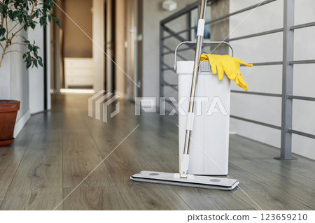 Cleaning supplies: mop, gloves, bucket with wringer on wooden laminate floor 123659210