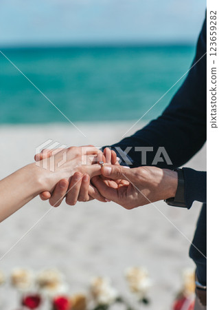 Closeup man putting engagement ring on woman hand on the beach Closeup man putting engagement ring on woman hand on the beach 123659282