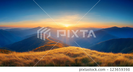 breathtaking sunrise over rolling mountains, with golden grass in foreground and vibrant sky. scene evokes tranquility and natural beauty 123659398