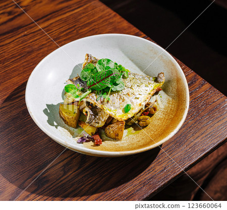 Grilled fish served with potatoes and fresh herbs at a restaurant 123660064