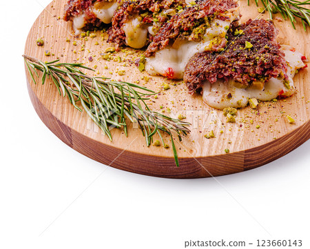 Savory meat dish with cheese and nuts on a wooden platter Savory meat dish with cheese and nuts on a wooden platter 123660143