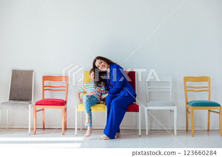 Mother and son on chairs in the interior of a white room Mother and son on chairs in the interior of a white room 123660284