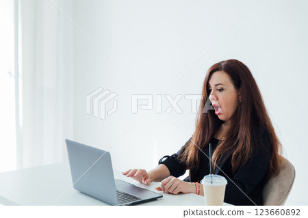 Businesswoman brunette sitting at desk surprised online laptop Businesswoman brunette sitting at desk surprised online laptop 123660892