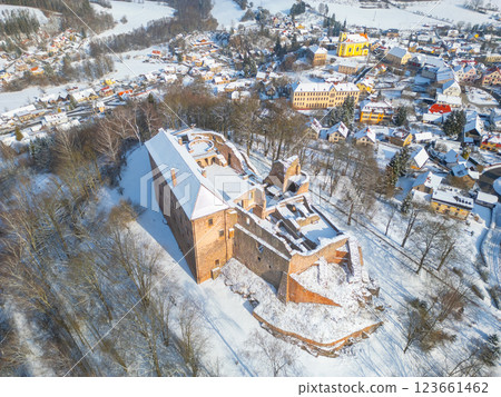 Pecka castle stands majestically in winter, dusted in snow. Surrounding landscape features quaint village homes, creating a picturesque view in Czechia during the cold season. 123661462