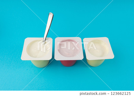 Yogurt cups set, pink and yellow fruit yoghurt in plastic pots, milk pudding container with spoon Yogurt cups set, pink and yellow fruit yoghurt in plastic pots, milk pudding container with spoon 123662125