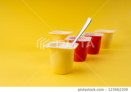 Yogurt cups set, pink and yellow fruit yoghurt in plastic pots, milk pudding container with spoon 123662209