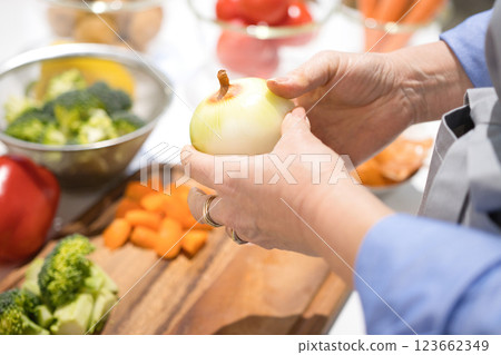 Hands of a middle-aged woman cutting vegetables 123662349
