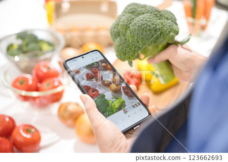 一位中年婦女的手用智慧型手機拍攝烹飪食材 一位中年婦女的手用智慧型手機拍攝烹飪食材 123662693