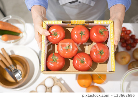 Middle-aged woman's hand holding a box of fresh tomatoes 123662696
