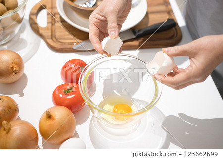 Middle-aged woman's hand holding freshly cracked eggs in a bowl 123662699