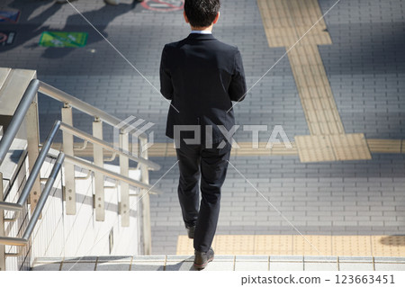 A middle-aged businessman descending the stairs in a city street during the day in winter 123663451