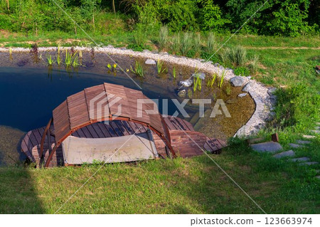 Pretty wooden pier at natural swimming pond or pool - NSP - purifying water without chemicals through biological filters and plants Pretty wooden pier at natural swimming pond or pool - NSP - purifying water without chemicals through biological filters and plants 123663974