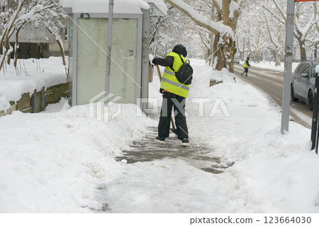 Municipal Employee Shoveling Near Bus Shelter 123664030