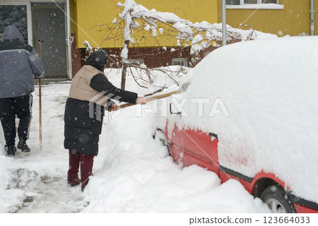 Senior Shoveling Snow from Parked Car in Residential Area Senior Shoveling Snow from Parked Car in Residential Area 123664033
