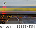 Photographing a train passing through a railroad crossing at dusk using a slow shutter speed 123664564