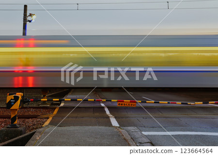 使用慢速快門拍攝黃昏時分穿越鐵路道口的火車 123664564