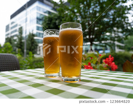 Two beer glasses at outdoor cafe, cold pint glass on checkered tablecloth table, cool condensation Two beer glasses at outdoor cafe, cold pint glass on checkered tablecloth table, cool condensation 123664820