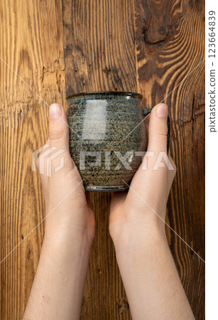 Hand Holds Cup, Empty Cup in Hands, Coffee Mug, Teacup Mockup, Cup in Arms on Wooden Table Hand Holds Cup, Empty Cup in Hands, Coffee Mug, Teacup Mockup, Cup in Arms on Wooden Table 123664839