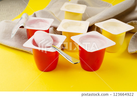 Yogurt cups set, pink and yellow fruit yoghurt in plastic pots, milk pudding container with spoon 123664922