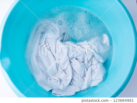 Hand laundry washing clothes in blue plastic basin Hand laundry washing clothes in blue plastic basin 123664981