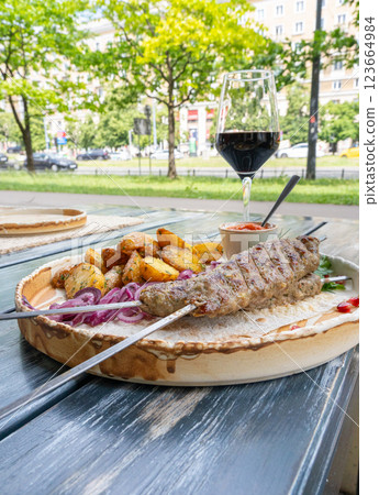 Georgian lula kebab with baked potatoes, sauce and greens. Grilled souvlaki, minced meat kebap, lamb on skewers Georgian lula kebab with baked potatoes, sauce and greens. Grilled souvlaki, minced meat kebap, lamb on skewers 123664984