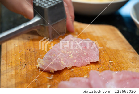 Tenderize meat, beating, hammering fillet pieces, cooking schnitzel process closeup Tenderize meat, beating, hammering fillet pieces, cooking schnitzel process closeup 123665020