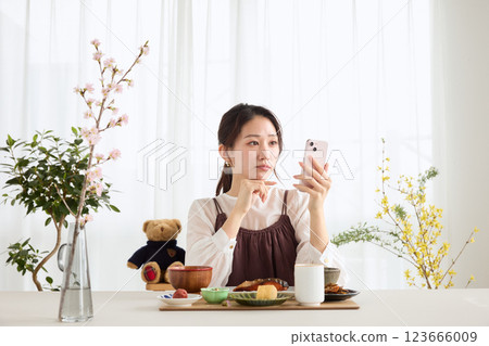 A woman looking at her smartphone at breakfast A woman looking at her smartphone at breakfast 123666009