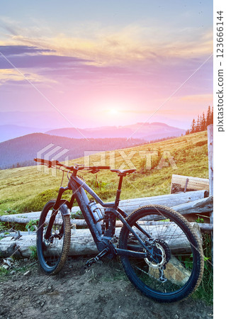 Black electric mountain bike on the dirt trail in the mountains at sunset (no people). Black electric mountain bike on the dirt trail in the mountains at sunset (no people). 123666144