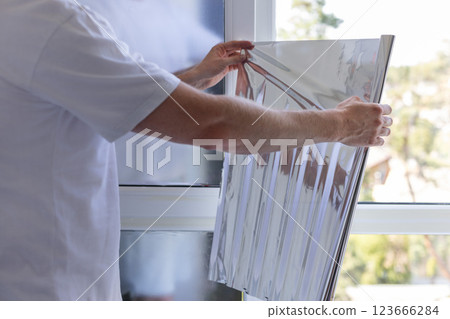 Man holding unrolled windows sun protection film. Man holding unrolled windows sun protection film. 123666284