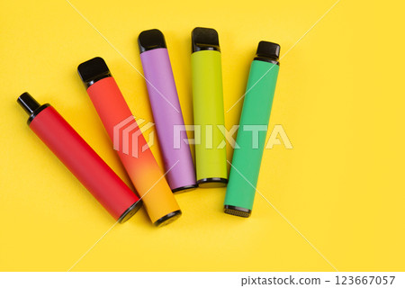 Layout of colorful disposable electronic cigarettes on a yellow background. The concept of modern smoking 123667057