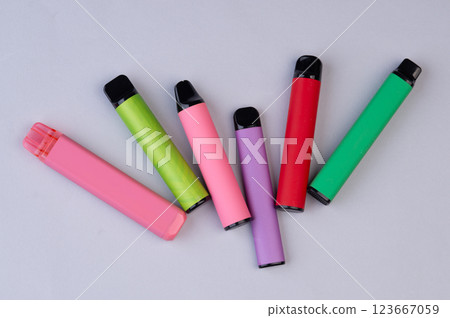Colorful disposable vape pens arranged on a light background. Modern electronic cigarettes in vibrant colors. 123667059