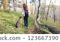 Young woman walking with a dog in an autumn forest 123667390