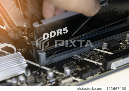 The technician is installing DDR5 RAM onto the motherboard. The technician is installing DDR5 RAM onto the motherboard. 123667468