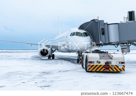 The tow truck approaches the white passenger aircraft at the jetway The tow truck approaches the white passenger aircraft at the jetway 123667474