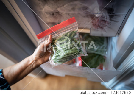 Hands with green beans from freezer in zip bag. Winter storage, fresh healthy homemade meal cooking 123667630