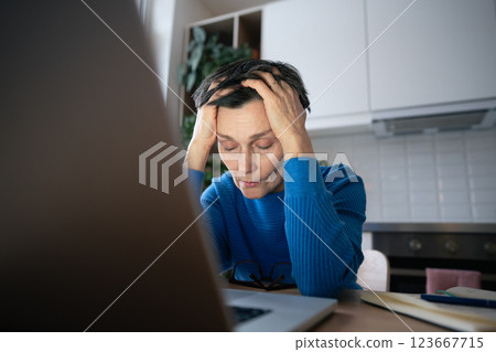 Burnout woman. Fatigued female slumped near laptop, battling eye strain from prolonged screen use 123667715