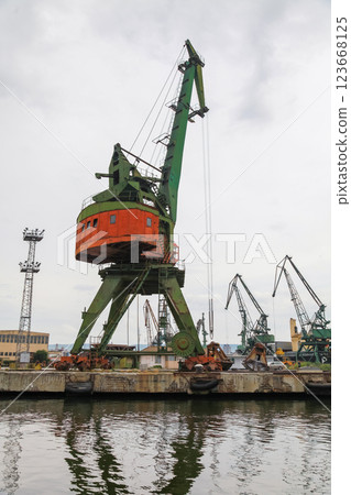 An industrial dockside crane stands prominently at a busy harbor 123668125